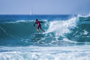 teenager surfing at the wave in tenerife playa de las americas - red wetsuits and beautiful wave