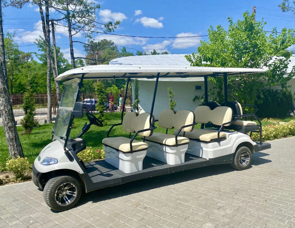 Golf cart for six person parking on fairway on a sunny day.