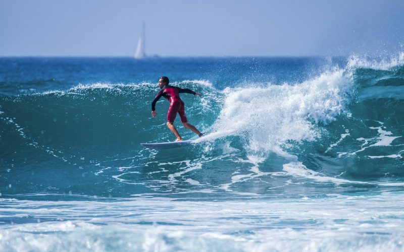 teenager surfing at the wave in tenerife playa de las americas - red wetsuits and beautiful wave