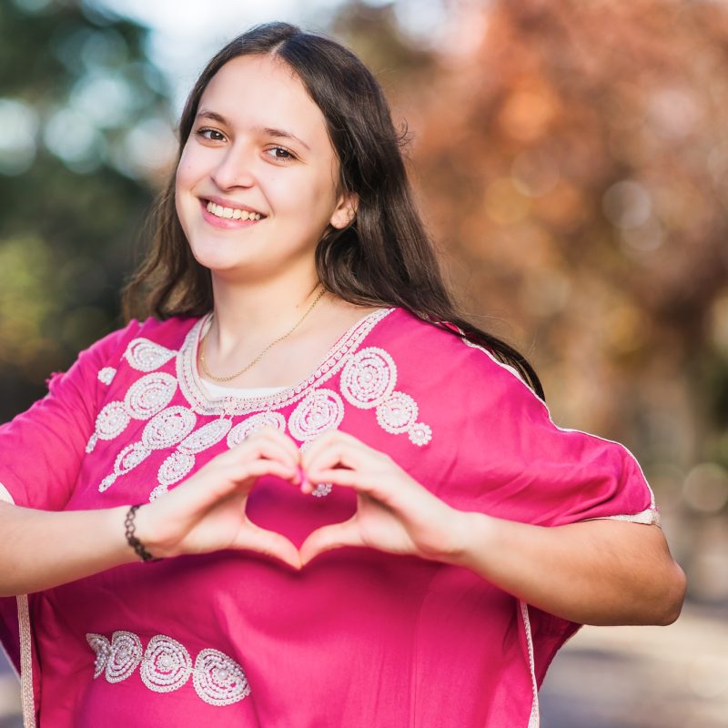 Young Moroccan woman doing heart love shape with hands with traditional dress. InspireInclusion