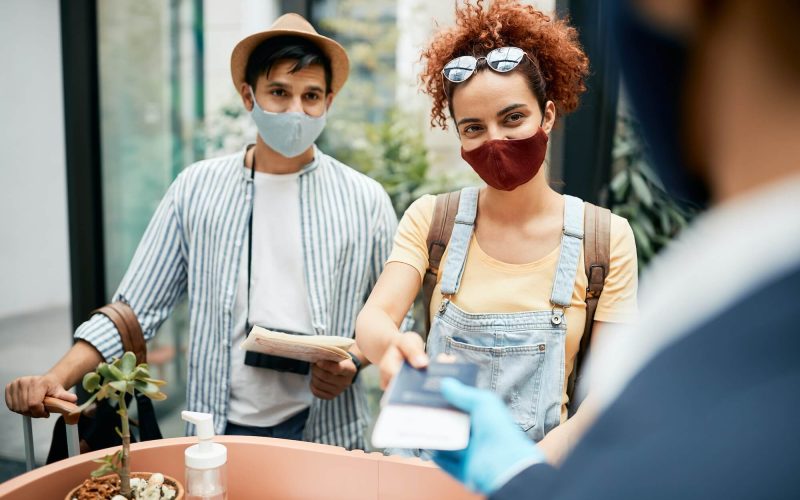 young-traveling-couple-wearing-protective-face-mask-during-check-in-at-hotel-reception-1-1.jpg